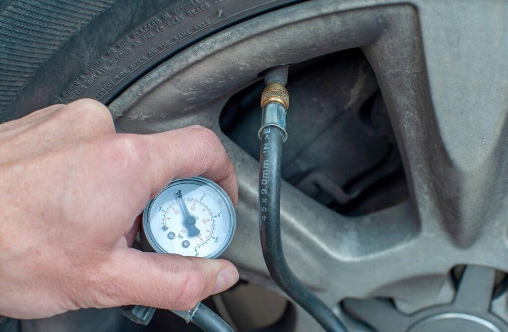 Man checking tire pressure and inflating tire.