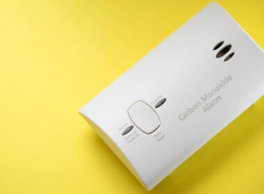 A carbon monoxide detector set against a yellow background.