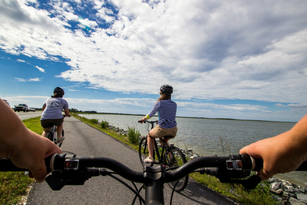 People riding their bikes along the water while on their Assateague Island Camping trip. 