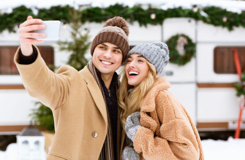 A couple taking a photo in the snow enjoying their new RV cell phone booster.
