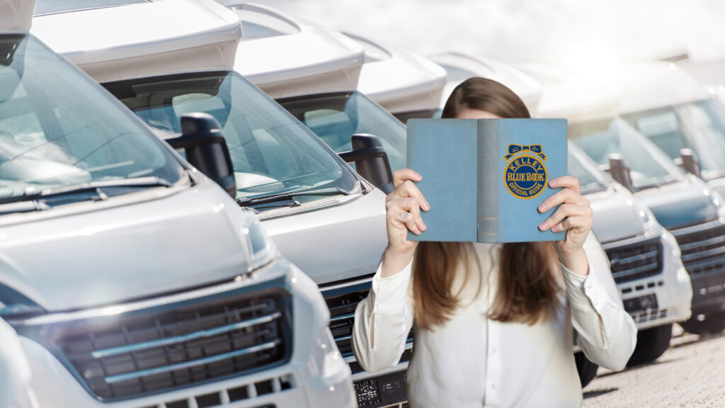 A woman holds up a Kelley Blue book while looking for RVs to buy.