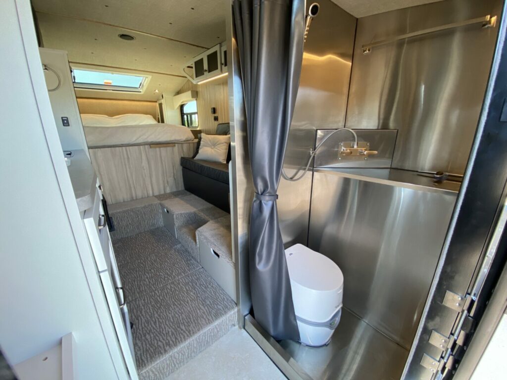Interior shot of a truck camper showing the wet bath, bed, and couch. The small size is sometimes a truck camper regrets.