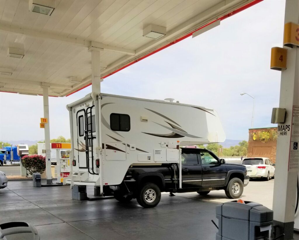 Truck camper at a gas station pump fueling up 