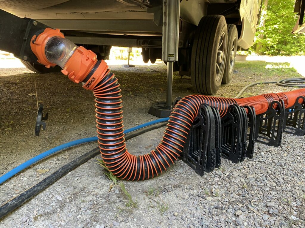 An RV sewer hose connected to an RV with a "U" shape in the middle to prevent smells or sewer flies getting in