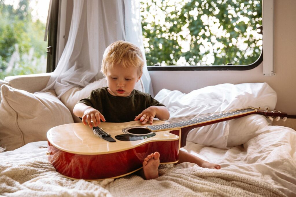 Little boy in RV bed with guitar 