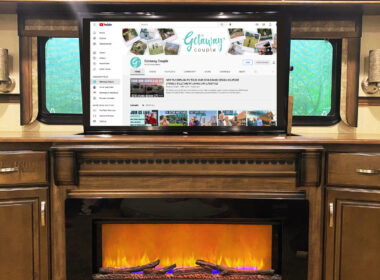 An RV living room with a fire burning and a TV playing.
