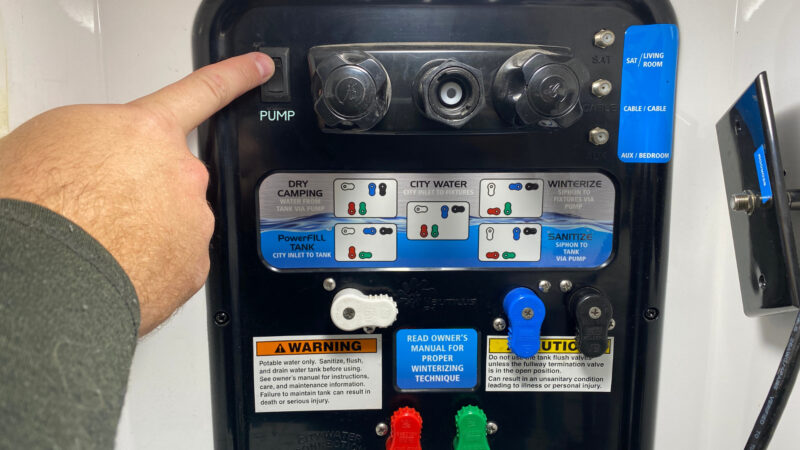 Hand pushes switch to turn off RV water pump