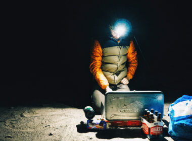 A headlamp is one of many boondocking must-haves and it cuts through the blackness of night as a camper kneels by his stove.