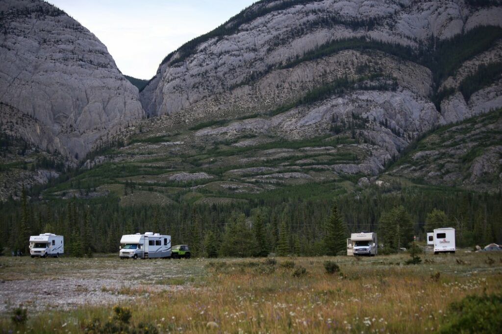 RVs camping in Canada with giant rock formations behind them.