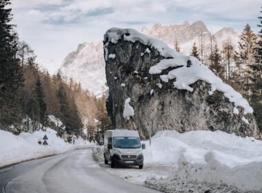 An RV drives through the snowy winter mountains.