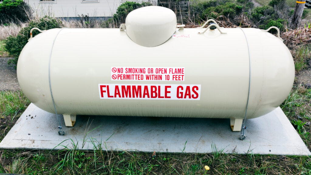 A large propane refill tank with the words "flammable gas" on the side 