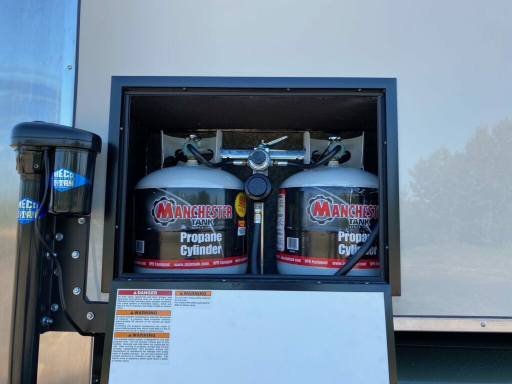 Two propane tanks inside the storage compartment of a truck camper 