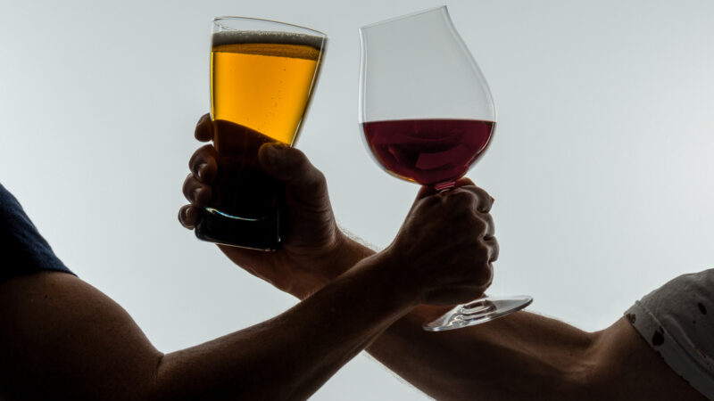 Beer and Wine glasses in hands of wrestling arms.