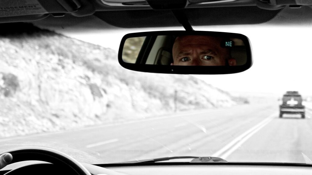 Worried man looks into his rear view mirror as he travels down the highway.