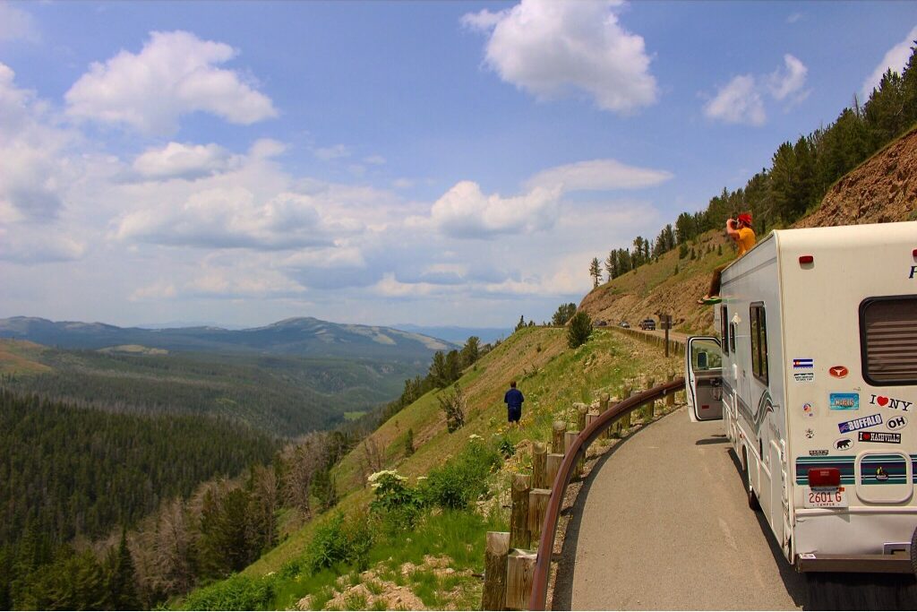 A motorhome stops along a hillside to let passengers look out over the landscape.