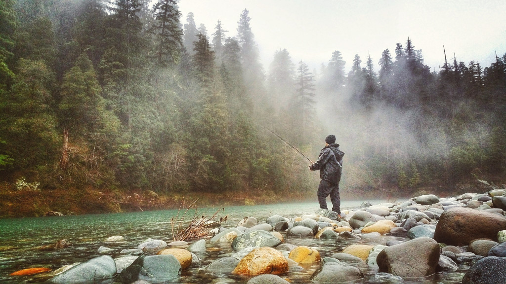 A man fishes along the steaming Smith River where you can experience free camping California.