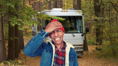 A man regrets parking his large motorhome in a small space surrounded by trees.