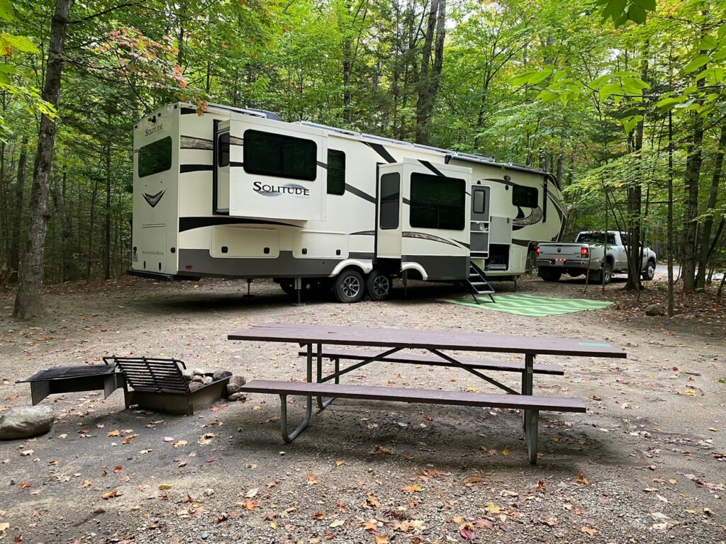 A large RV fits into a large campground with tree privacy in a state park campground.
