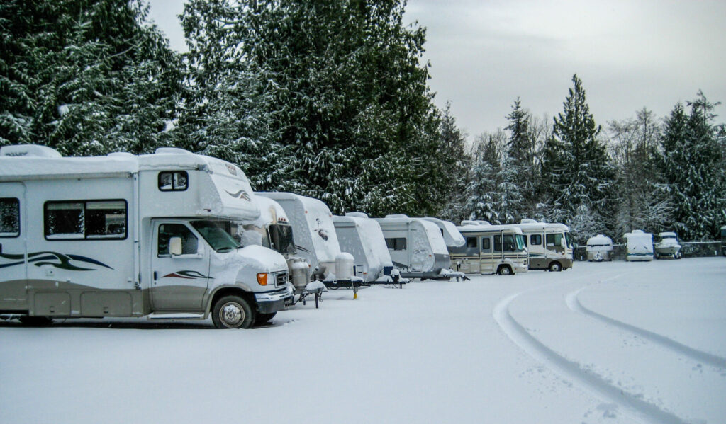 A row of RVs covered in snow in an RV park 