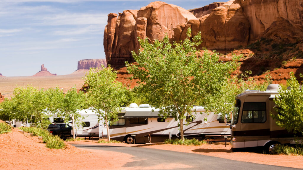 A row of RVs in a campground overlooking rock formations in the desert 