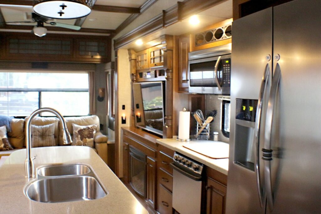 The kitchen of a large fifth wheel with paper towel and kitchen utensils left out on the counter.