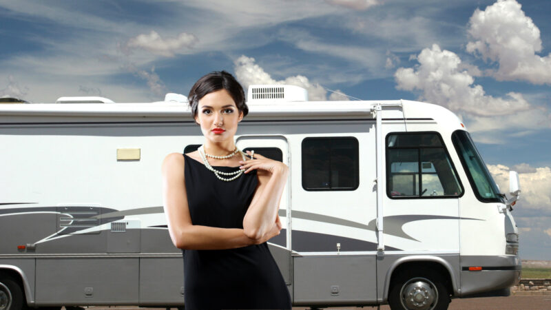 A luxurious woman stands in front of her RV.