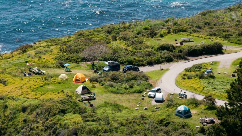 Aerial view of tents and RVs at a campground along the ocean coast.