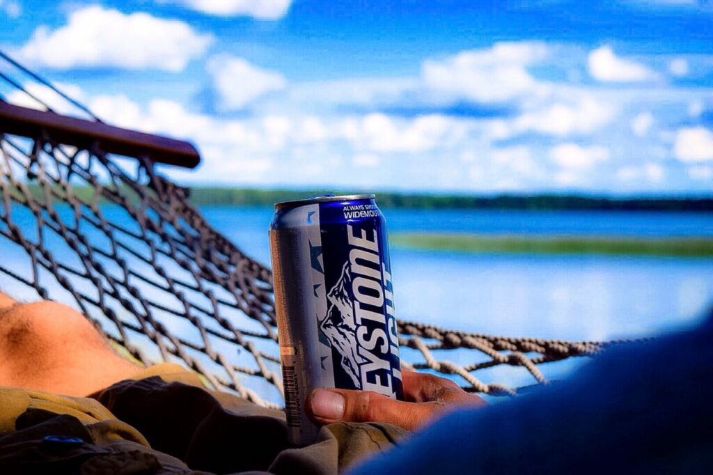 A man in a hammock holding a cheap beer and enjoying the view 