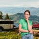 A woman stands in front of her campsite and ponders if her Airstream Basecamp trailer is worth the money.