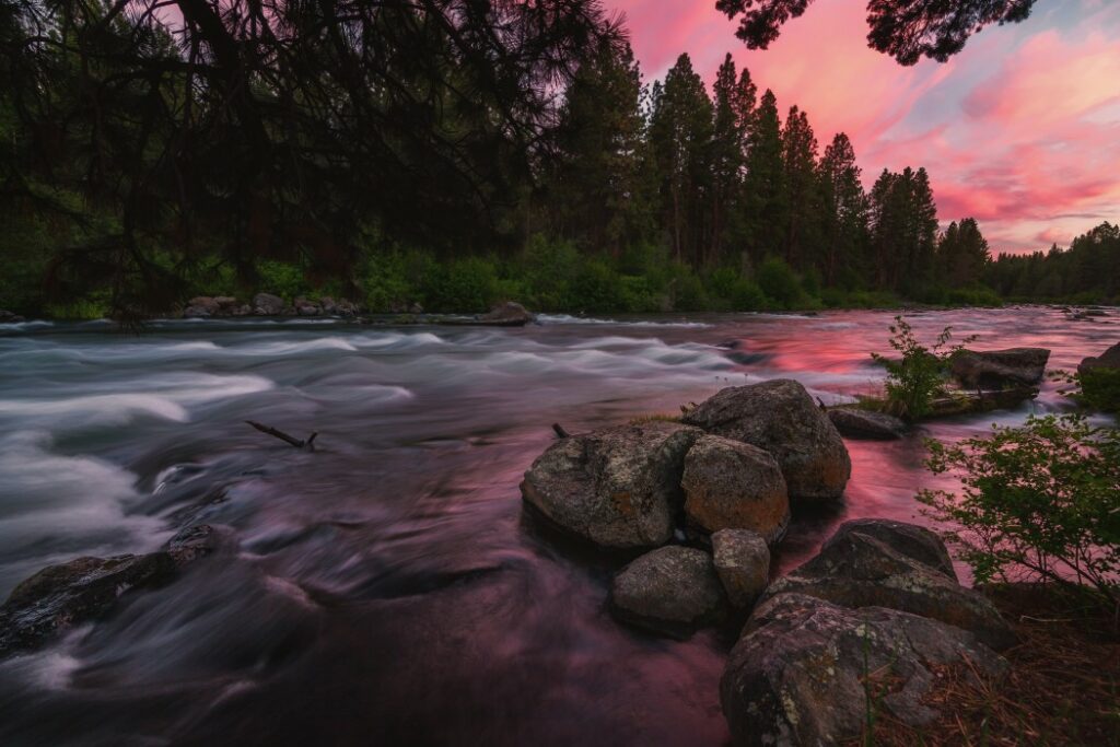 Pink, cloudy sunset at the river in Deschutes National Forest, Oregon.