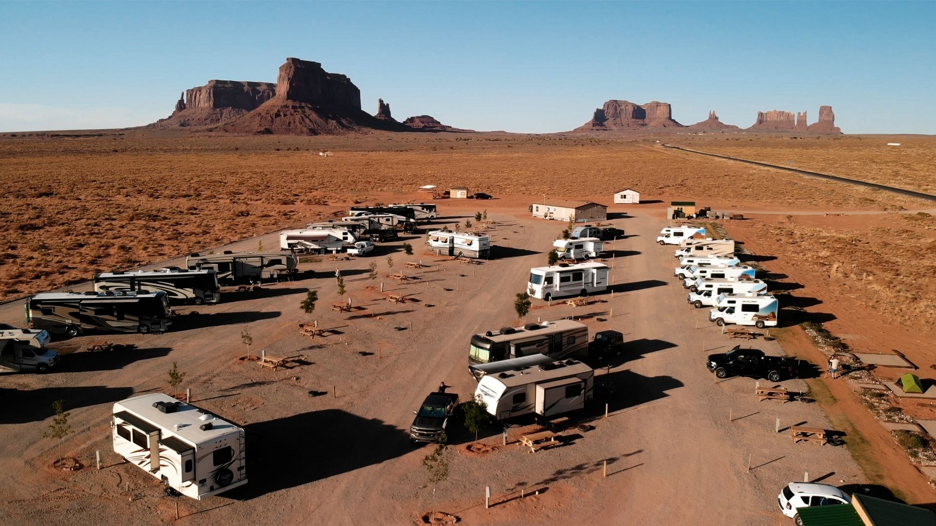 Aerial view of RV campground in Utah with rows of RVs and rock formations in the distance.