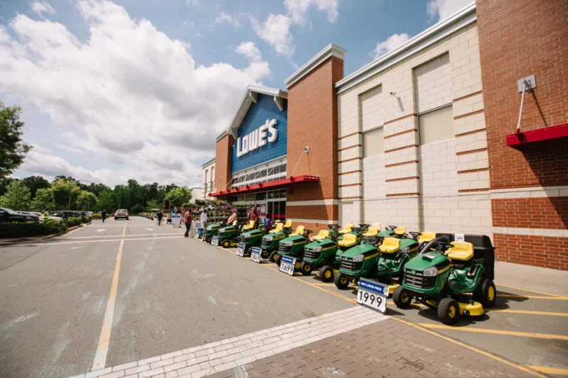 The outside of a Lowe's hardware store with rows of tractors in front.