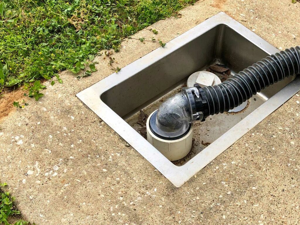 A clear sewer hose connector attaches a hose to a dump station at a campground.