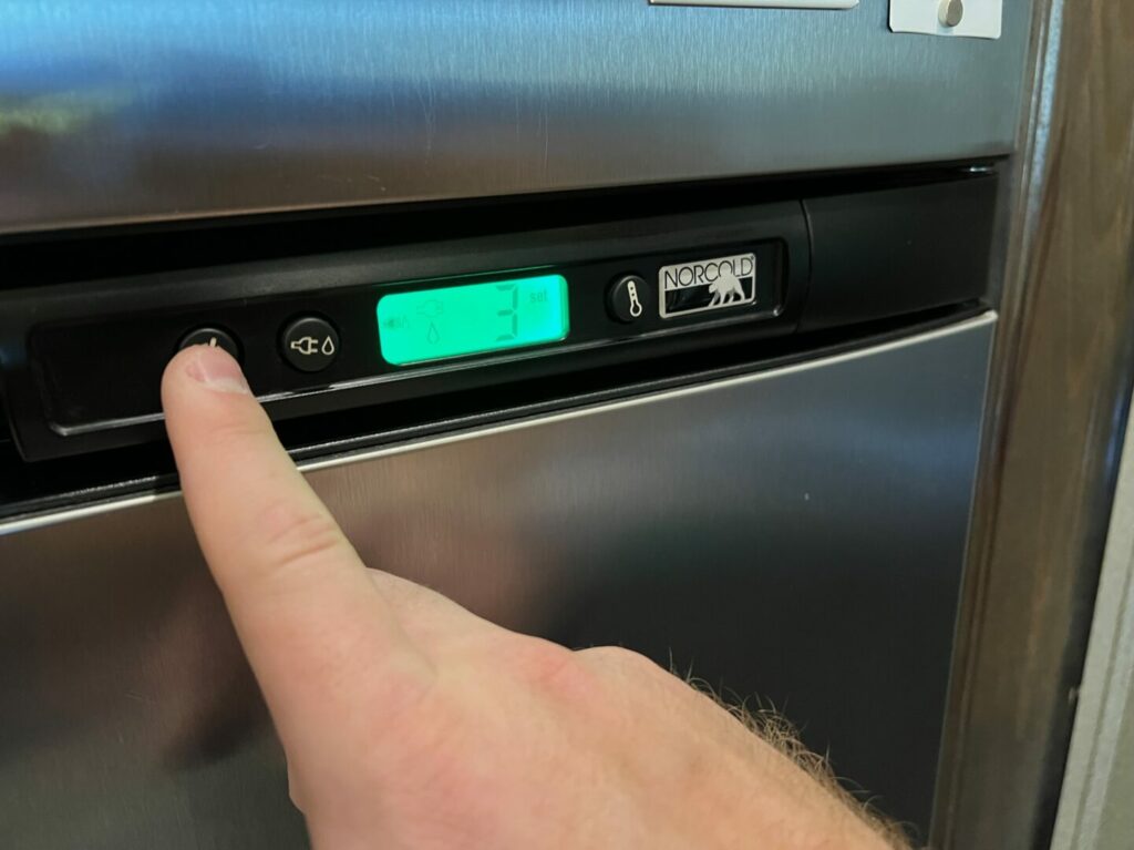 A hand turns off the propane power to their 3-way RV fridge. 