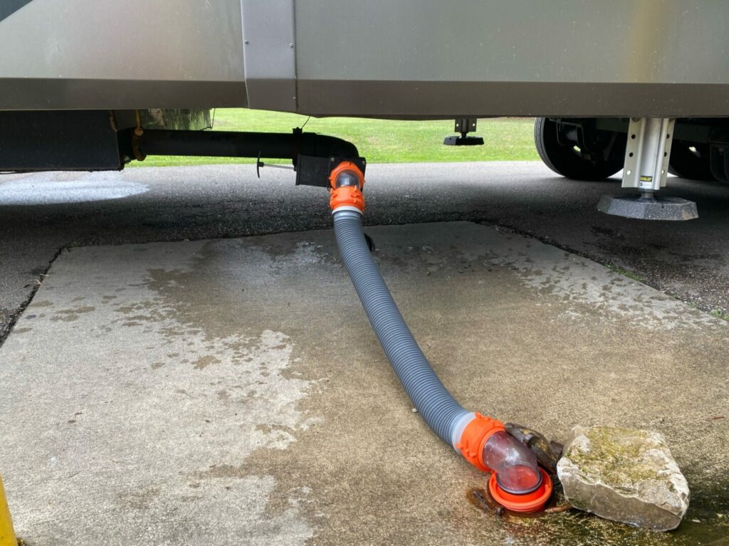 A sewer hose connected to the RV at a dump station.