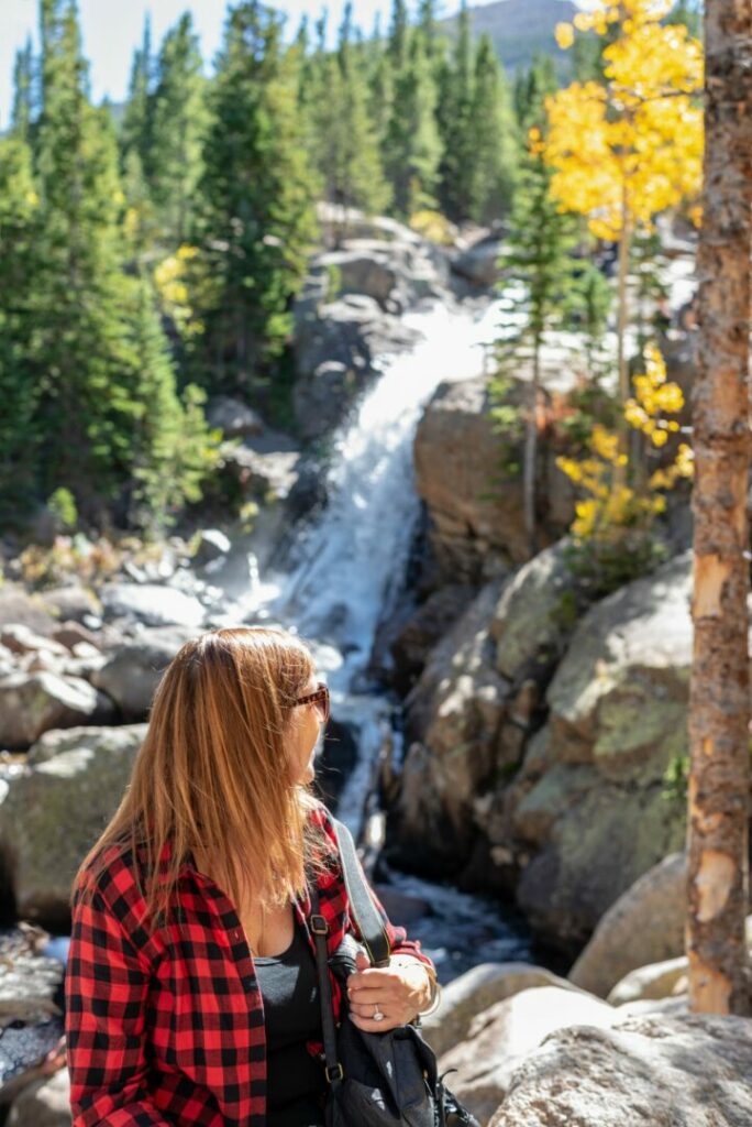 A woman near a waterfall in Rocky Mountain National Park in the fall.