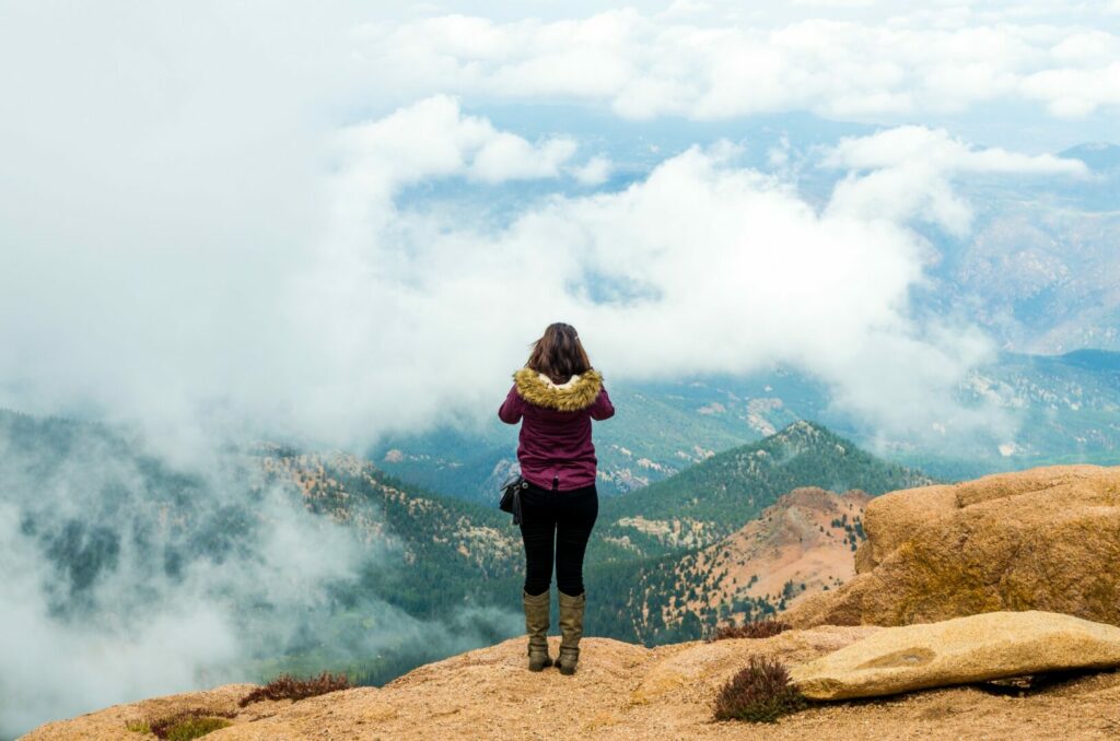 A girl enjoying the beauty of mountain and cloud and taking photographs from the top of Pike's Peak in Colorado.