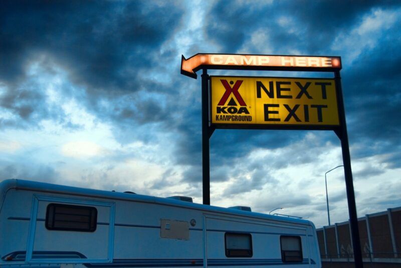 A dark KOA sign is not appealing to enter with a dark cloudy sky behind it.