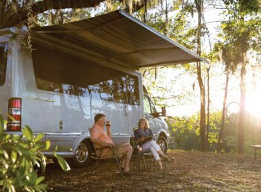 A couple relaxes with win outside of their Airstream Atlas touring coach.