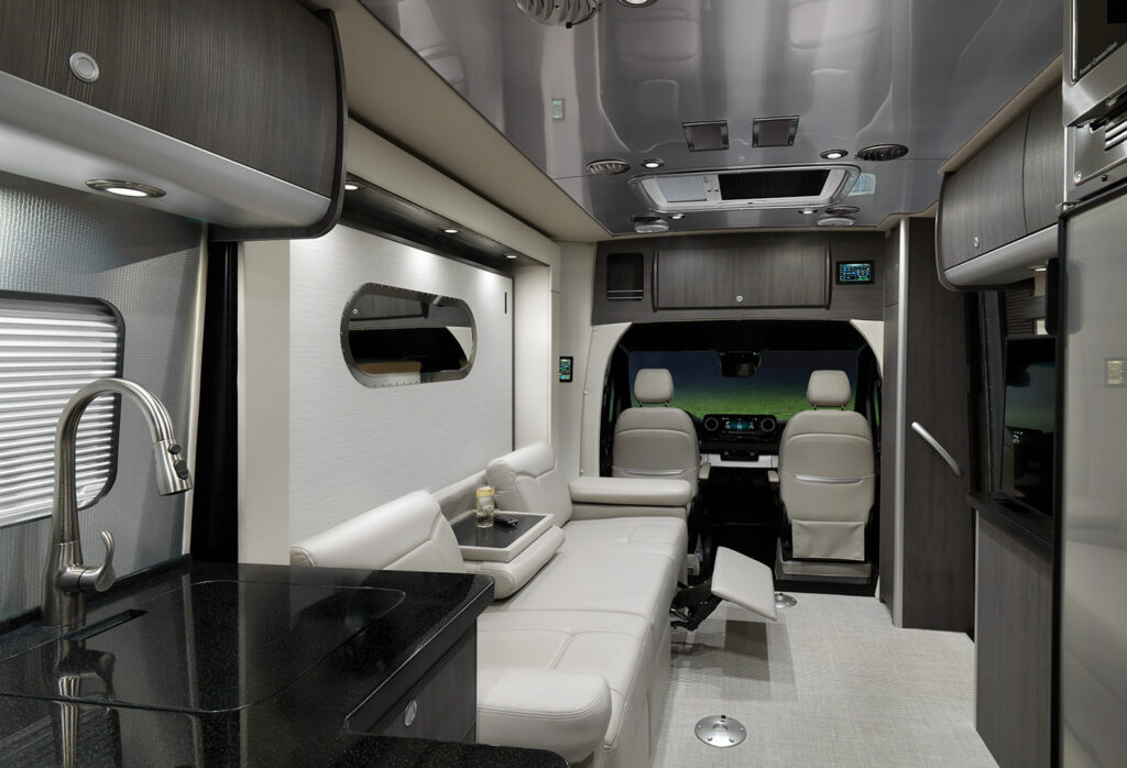 Interior of an Airstream Atlas looking towards the front seats of the coach from the kitchen.