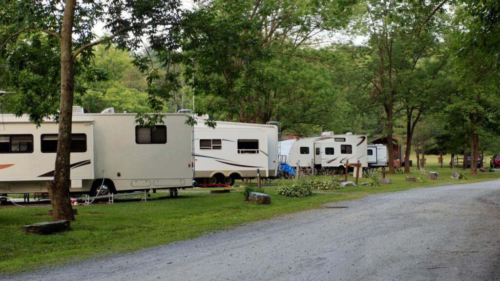 An RV Resort with several large fifth wheels parked diagonally along the paved drive, each with their own hookups.