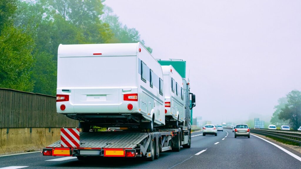 RVs on the back of a semi being transported on the highway 