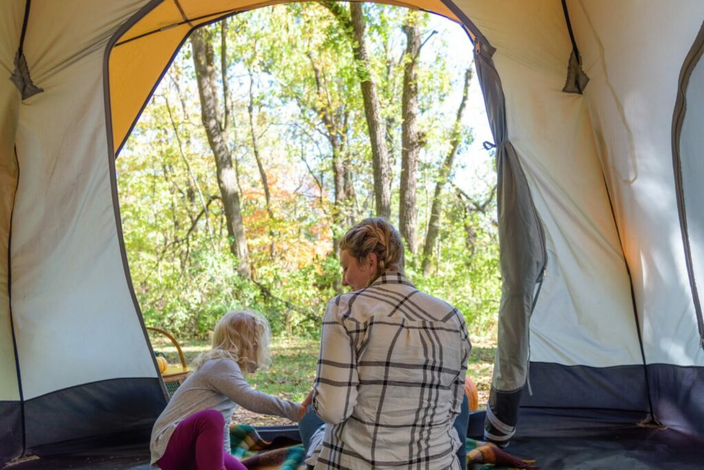 Mom and daughter camping in tent in New York State Park.