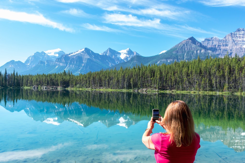 A woman hiker uses her cell phone to photograph the mountains in a national park.