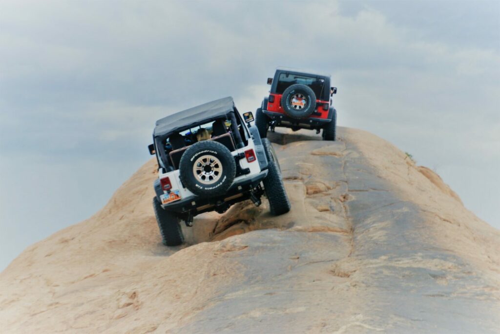 Two Jeeps climbing a rock in Moab, Utah.