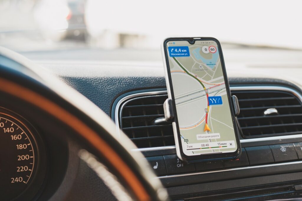 Close up of a navigation app giving directions mounted to the dash of a vehicle.