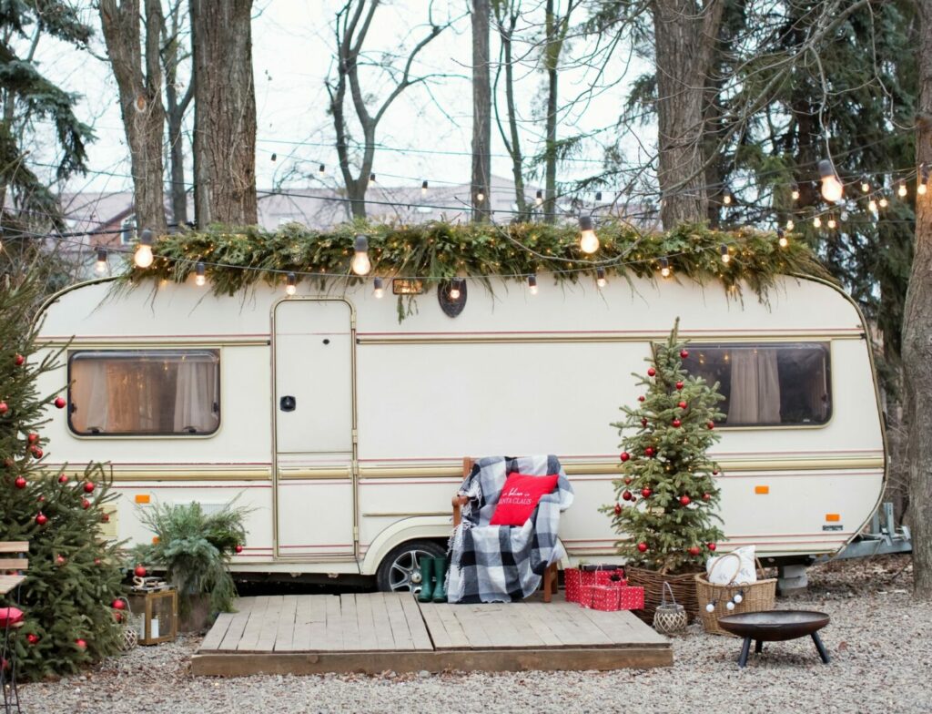 A travel trailer decorated for the holidays with garland, lights, and throw pillows.