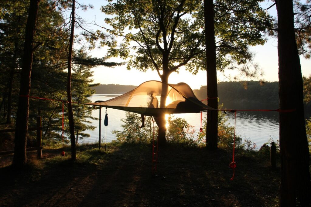 Hammock camping in Northern Michigan as the sun sets over an inland lake.