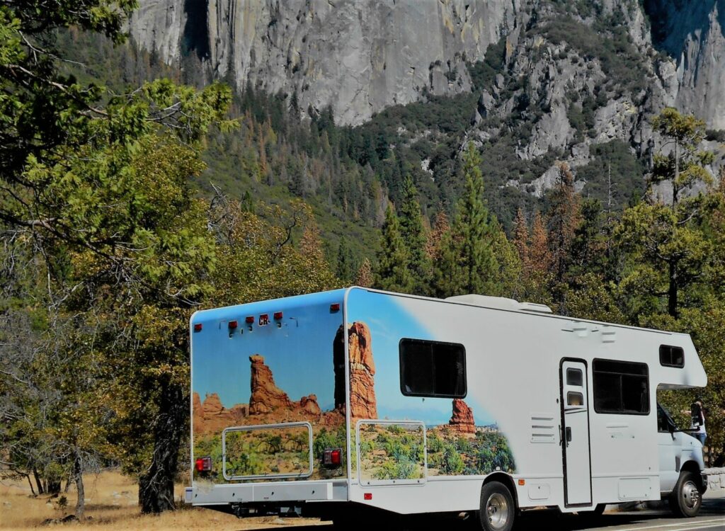 A rental RV is parked against a granite wall in Yosemite National Park.