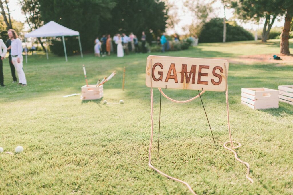 A wooden sign for yard games outside of a clubhouse.
